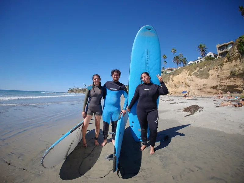 Three people standing together on the sand with surfboards
