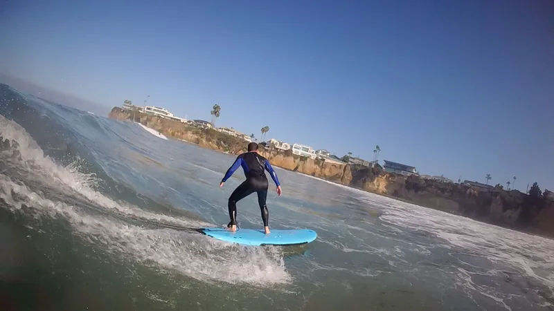 A surfer riding a small breaking wave on a blue board
