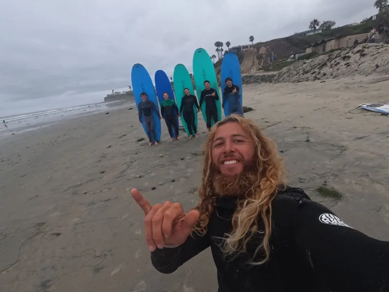 Will Machado taking a beach selfie with students and their surfboards